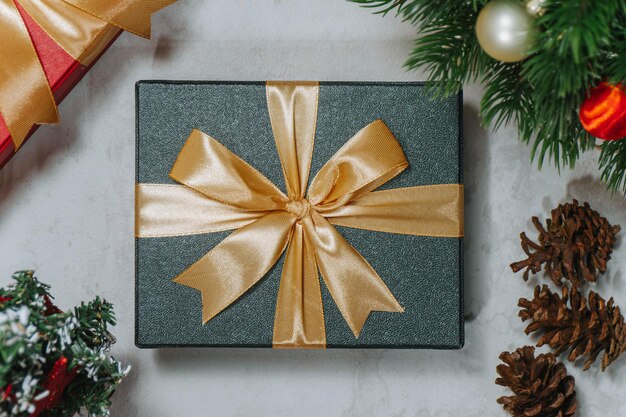 Boże Narodzenie pudełko prezentów owinięte złotą wstążką otoczone ozdobami świątecznymi Dekoracje świąteczne