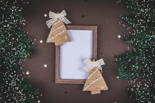 Boże Narodzenie skład karty na brązowym tle z gałęzi jodły pokryte śniegiem i makiety.