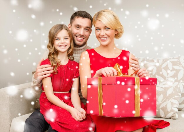 Boże Narodzenie, święta, szczęście i koncepcja ludzi - uśmiechnięta rodzina z dużym czerwonym pudełkiem w domu