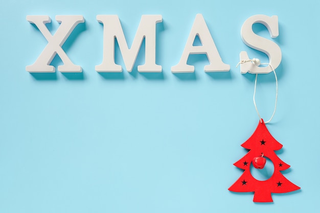 Zdjęcie boże narodzenie tekst z białych liter i czerwone zabawki świąteczne dekoracje drzewo na niebieskim tle