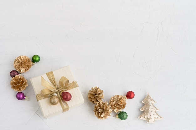Boże Narodzenie tło. Świąteczne dekoracje i prezent lub pudełko ozdobione złotą wstążką na białym tle. Widok z góry, kopia przestrzeń.