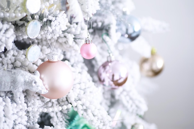 Boże Narodzenie tło wakacje. Srebrna i kolorowa bombka zawieszona na ozdobionym drzewie z bokeh i śniegiem, kopia przestrzeń.