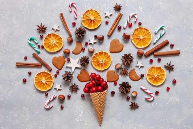 Boże Narodzenie z czerwonymi kulkami, cukierkami, ciasteczkami, przyprawami, suchymi plasterkami pomarańczy w waflu.
