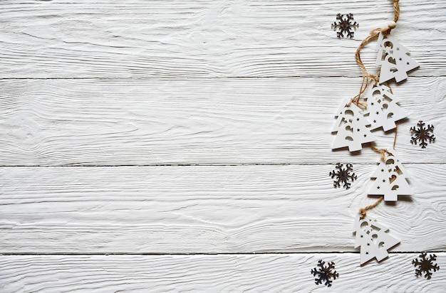 Zdjęcie bożenarodzeniowe dekoracje na białym drewnianym tle. białe drewniane jodły na koronce i srebrne płatki śniegu. zimowe tło. widok z góry.