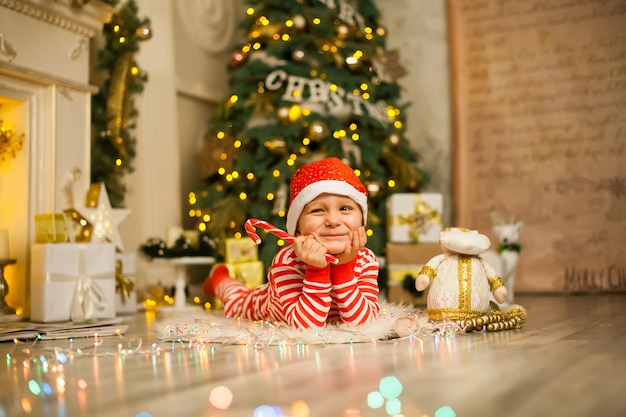 Bożenarodzeniowy chłopiec z czerwoną cukierek trzciną i Santa kapeluszem