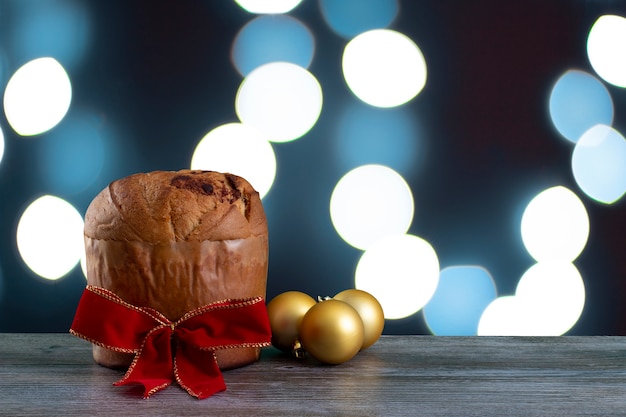 Zdjęcie bożenarodzeniowy czekoladowego torta panettone z czerwoną faborkiem w błękitnym lekkim tle, panetone