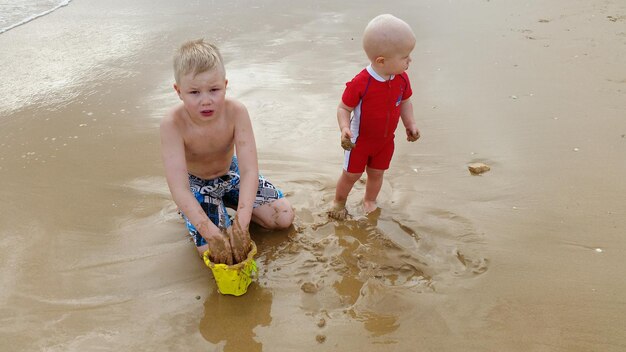 Bracia i siostry bawiący się na piasku na plaży