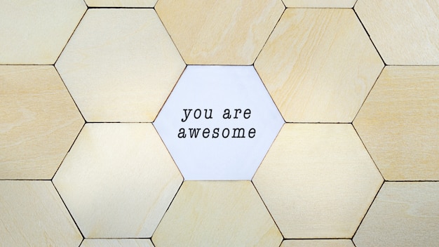 Zdjęcie brakującego drewnianego sześciokąta w puzzlach, odsłaniającego słowa you are awesome w konceptualnym obrazie rozwoju osobistego i optymizmu
