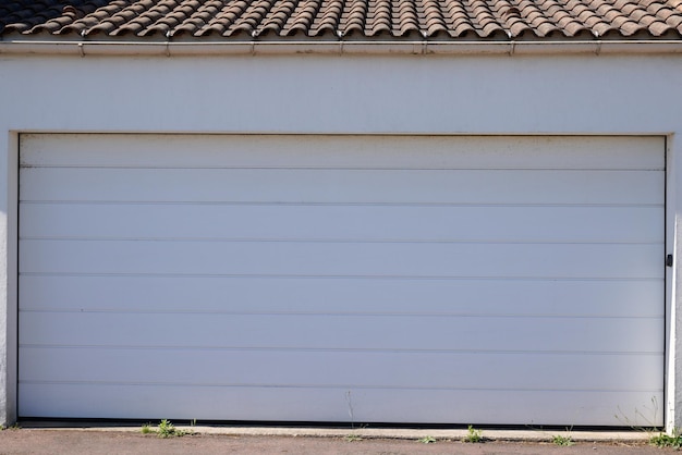 Brama garażowa segmentowa duża biała na fasadzie budynku domu zamknięta