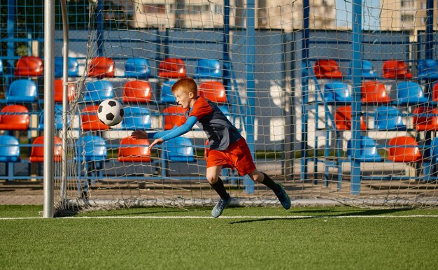 Zdjęcie bramkarz juniorów łapie piłkę podczas obrony bramki w meczu piłki nożnej. trening drużyny piłkarskiej lub turniej konkursowy