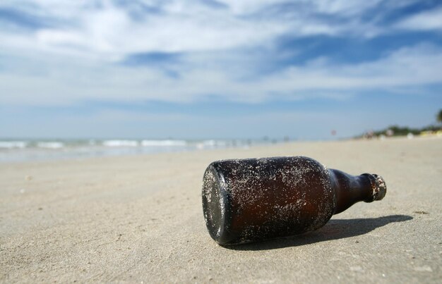Brązowa butelka leżąca na morskiej plaży