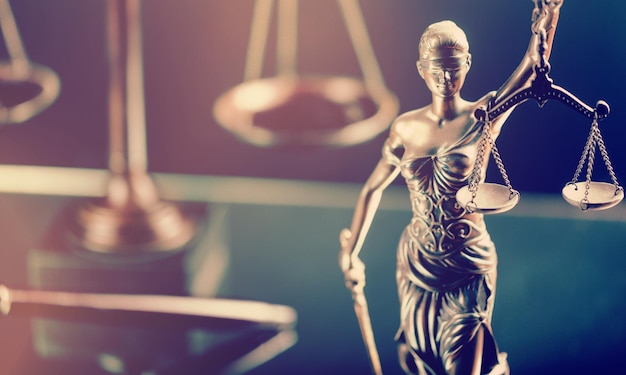 Brązowa statua Lady Justice z wagą i drewnianym młotkiem na biurku