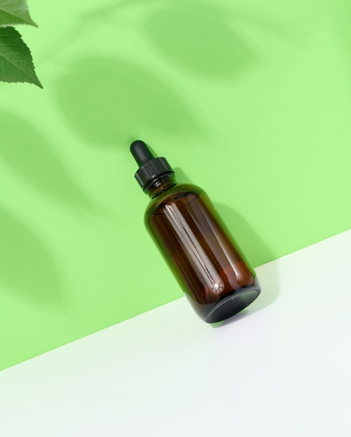 Brązowa szklana butelka z pipetą na zielonobiałym tle pojemnik na olejki aromatyczne i kosmetyki