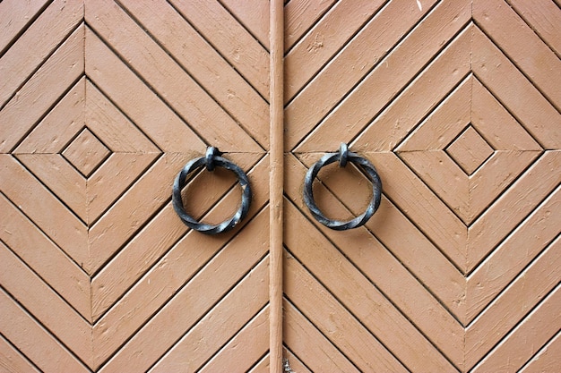 Brązowa vintage drewniana brama z żelaznymi pierścieniami w tle