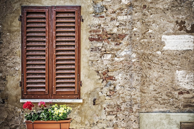 Brązowe okiennice w rustykalnej ścianie w San Gimignano we Włoszech