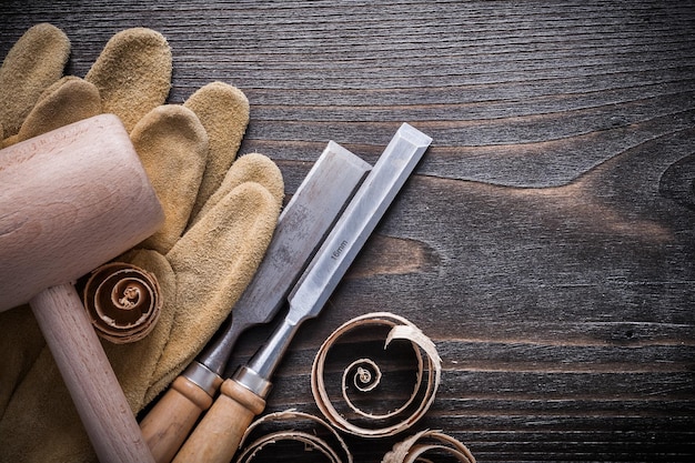 Brązowe skórzane rękawiczki płaskie dłuta drewniany młotek i wióry planistyczne na koncepcji konstrukcji deski z drewna vintage