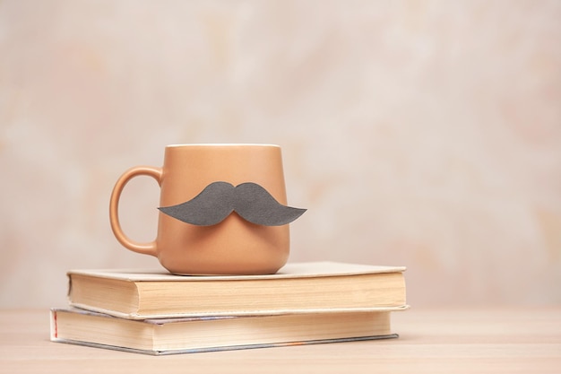 Brązowy kubek kawy z wąsami i książką Koncepcja Szczęśliwego dnia ojca