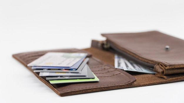 Brązowy portfel z kartami kredytowymi i studolarowymi rachunkami na białym tle