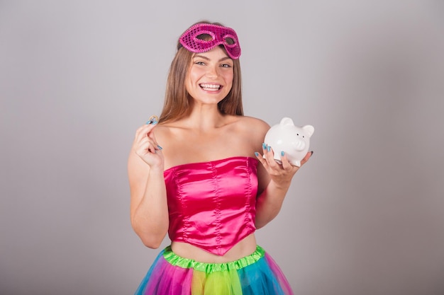 Brazylijska blondynka ubrana w różowe stroje karnawałowe trzymająca skarbonkę i monetę Zaoszczędź pieniądze inwestuj