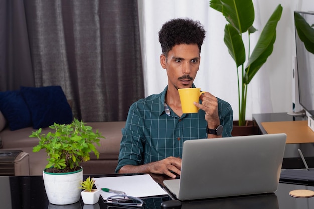 Brazylijski czarny biznesmen pracujący w domu Młody człowiek pracujący w biurze w ciągu dnia przy biurku z laptopem
