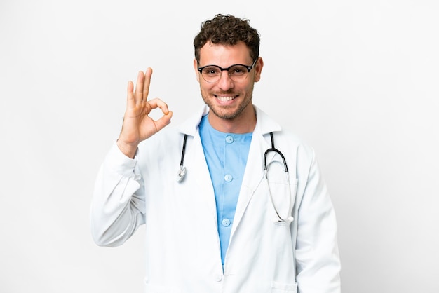 Brazylijski doktorski mężczyzna nad odosobnionym białym tłem pokazuje ok znaka z palcami