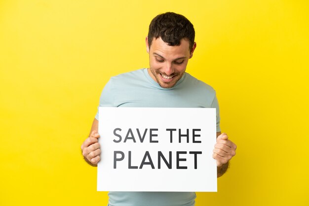 Brazylijski mężczyzna na odosobnionym fioletowym tle, trzymający afisz z tekstem Save the Planet