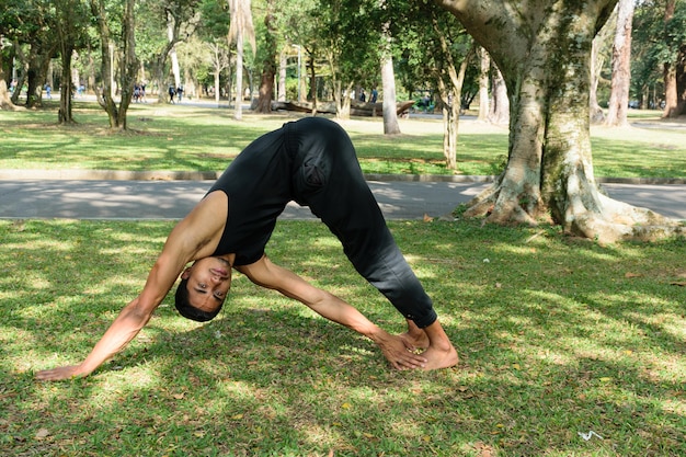 Brazylijski młody człowiek praktykujący jogę w publicznym parku w słoneczny dzień.