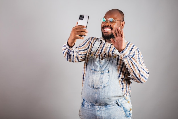Brazylijski murzyn trzymający smartfon w aplikacji selfie do rozmów wideo