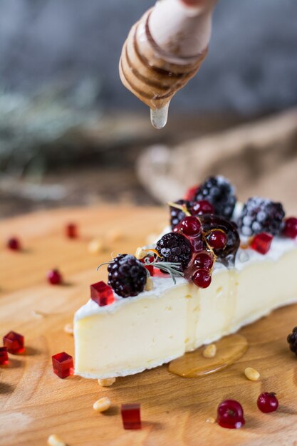 brie, camembert z miodem, marmoladą i orzeszkami pinii na desce serowej.