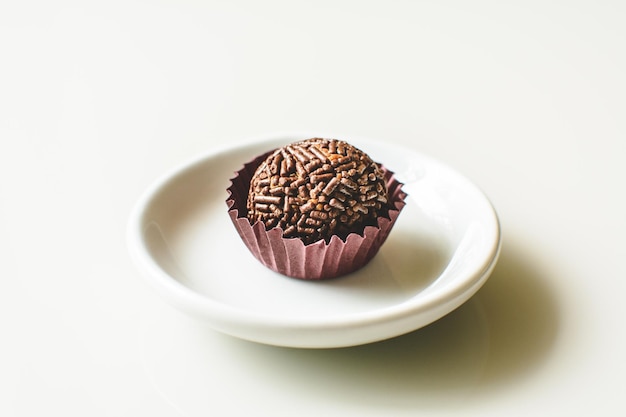 Brigadeiro, tradycyjne brazylijskie słodkie, na talerzu, białe tło.