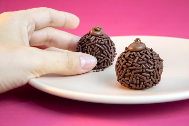 Brigadeiro tradycyjny brazylijski słodki Ręka podnosząca Brigadeiro na talerzu