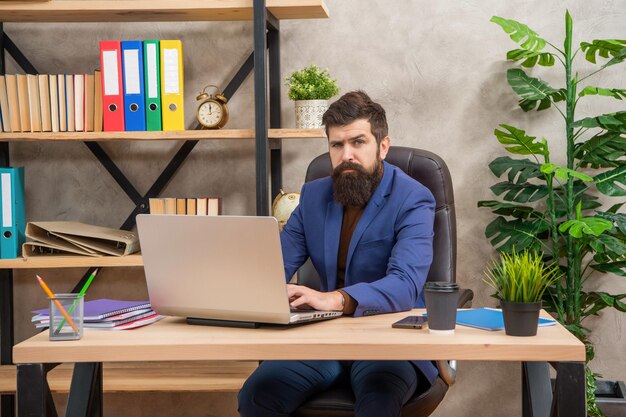 Brodaty biznesmen pracuje na laptopie w biurze pracownik biurowy