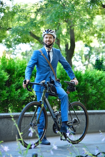 Brodaty biznesmen w kostiumu i hełmie z rowerem