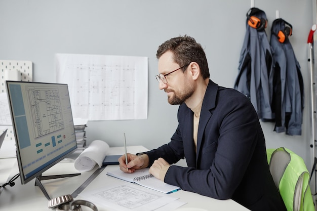 Zdjęcie brodaty inżynier używający komputera w biurze i projektujący projekty