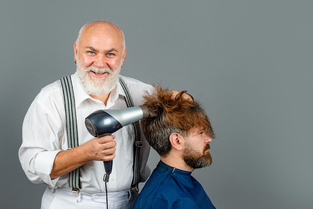 Brodaty mężczyzna coraz fryzurę przez fryzjera z suszarką do włosów u fryzjera. Szczęśliwy fryzjer trzymając suszarkę.