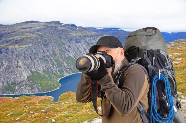 brodaty mężczyzna fotograf turystyczny z plecakiem fotografuje piękno natury