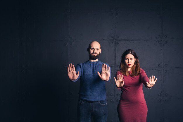Brodaty mężczyzna i kobieta w ciąży pokazują ręce stop
