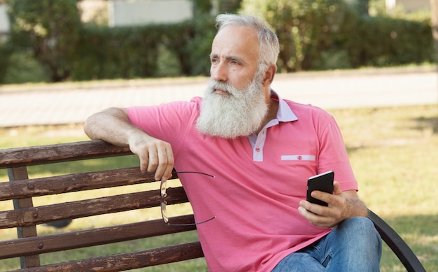 Brodaty mężczyzna na ławce za pomocą telefonu