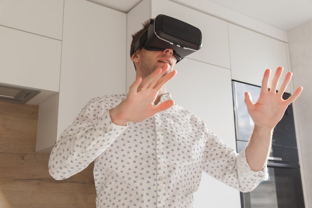 Brodaty mężczyzna nosi okulary wirtualnej rzeczywistości w nowoczesnym studio coworkingowym. Używanie smartfona z zestawem VR. Poziomy, niewyraźny
