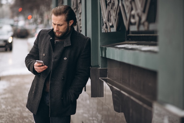 Brodaty mężczyzna opowiada na telefonie w ulicie w zimie