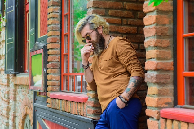 Brodaty mężczyzna pali papierosa stylowy hipster z dymem papierosowym zmysłowy mężczyzna palący