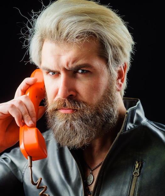 Brodaty mężczyzna rozmawia z telefonem w stylu retro, przystojny mężczyzna z poważnym facetem w stylu vintage ze słuchawką