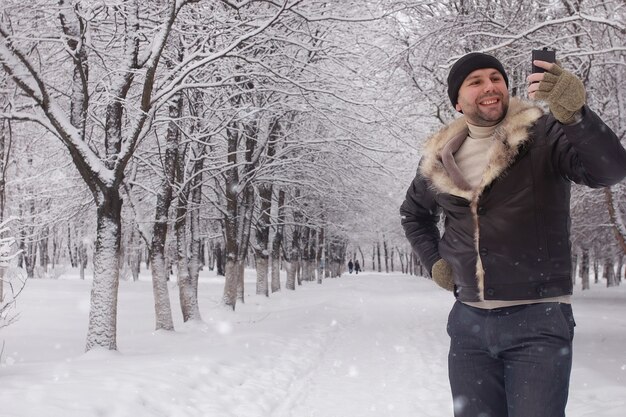 Brodaty mężczyzna spacerujący w sezonie śnieżnym w parku zimowym