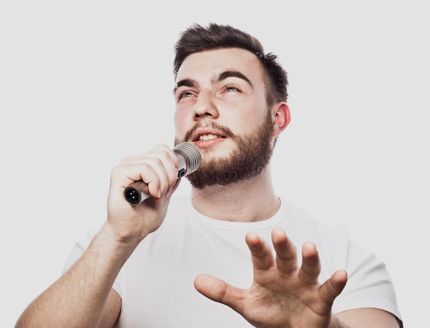 Brodaty mężczyzna śpiewa do mikrofonu Emocjonalny portret atrakcyjnego faceta z brodą na białym tle