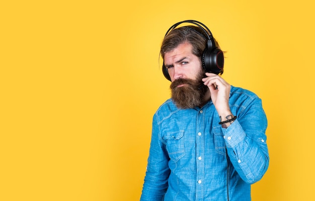 Brodaty mężczyzna w słuchawkach słucha muzyki koncepcja edukacji online audiobook kopia przestrzeń słuchaj ulubionej piosenki nowa technologia we współczesnym życiu cyfrowy hipster w zestawie słuchawkowym