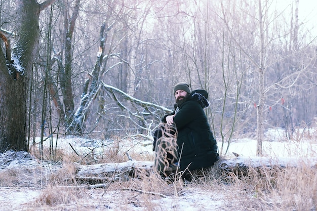 Zdjęcie brodaty mężczyzna w zimowym lesie. atrakcyjny szczęśliwy młody człowiek z brodą spacer w parku.