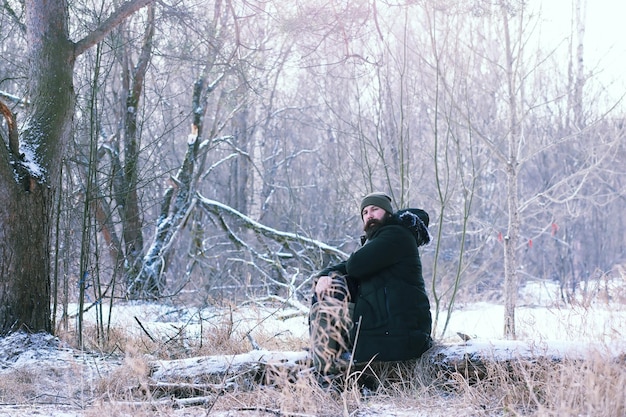 Brodaty mężczyzna w zimowym lesie. Atrakcyjny szczęśliwy młody człowiek z brodą spacer w parku.