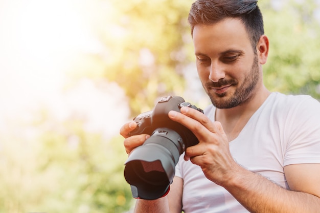 Zdjęcie brodaty młody człowiek patrząc na zdjęcia zrobione z dslr