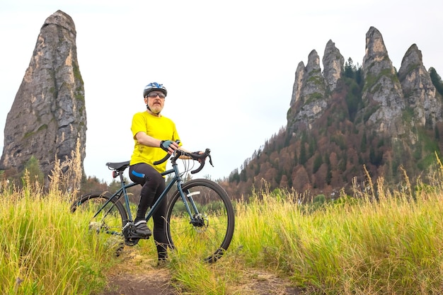 brodaty rowerzysta w żółtych ubraniach odpoczywa na rowerze na drodze w sporcie przyrody