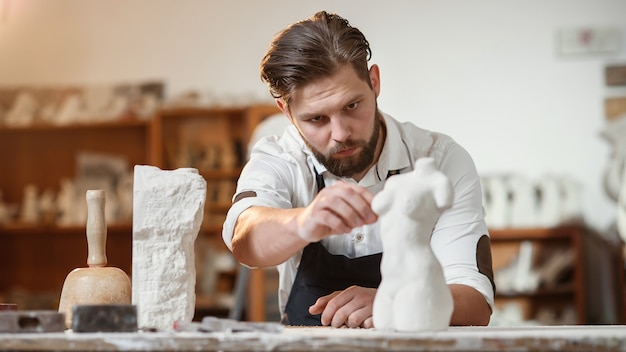 Brodaty rzeźbiarz mierzy kamienny korpus kobiety, aby wykonać kopię z wapienia w kreatywnym studio.